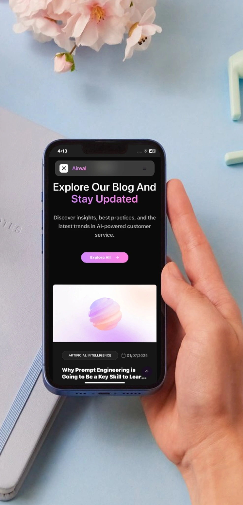 AiReal blog section on a mobile phone held in hand, showing AI-powered customer service articles